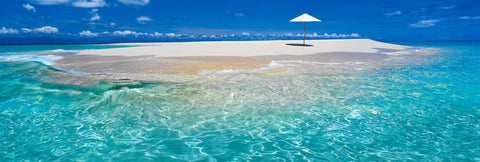 Umbrella stuck in the white sand of the Upolu Cay in the middle of the Great Barrier Reef in Queensland Australia