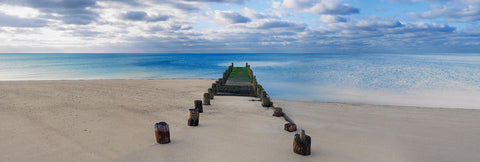 Wooden jetty half buried by the sand beach stretching out over the ocean in Cape Cod Massachusetts
