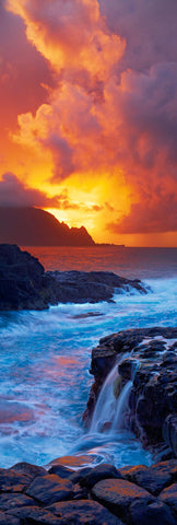 Waves crashing along the rock coast of Kaui Hawaii as the sun sets through the clouds and behind the Napali cliffs