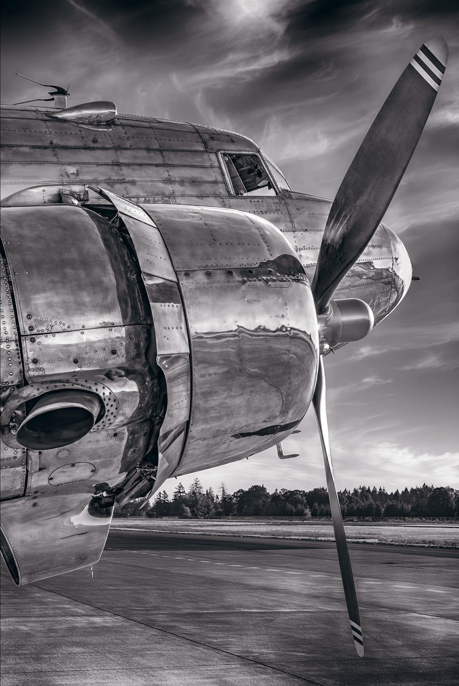Black and white close up side view of the engine and cockpit of a DC-3 airplane on a runway in Aurora Oregon