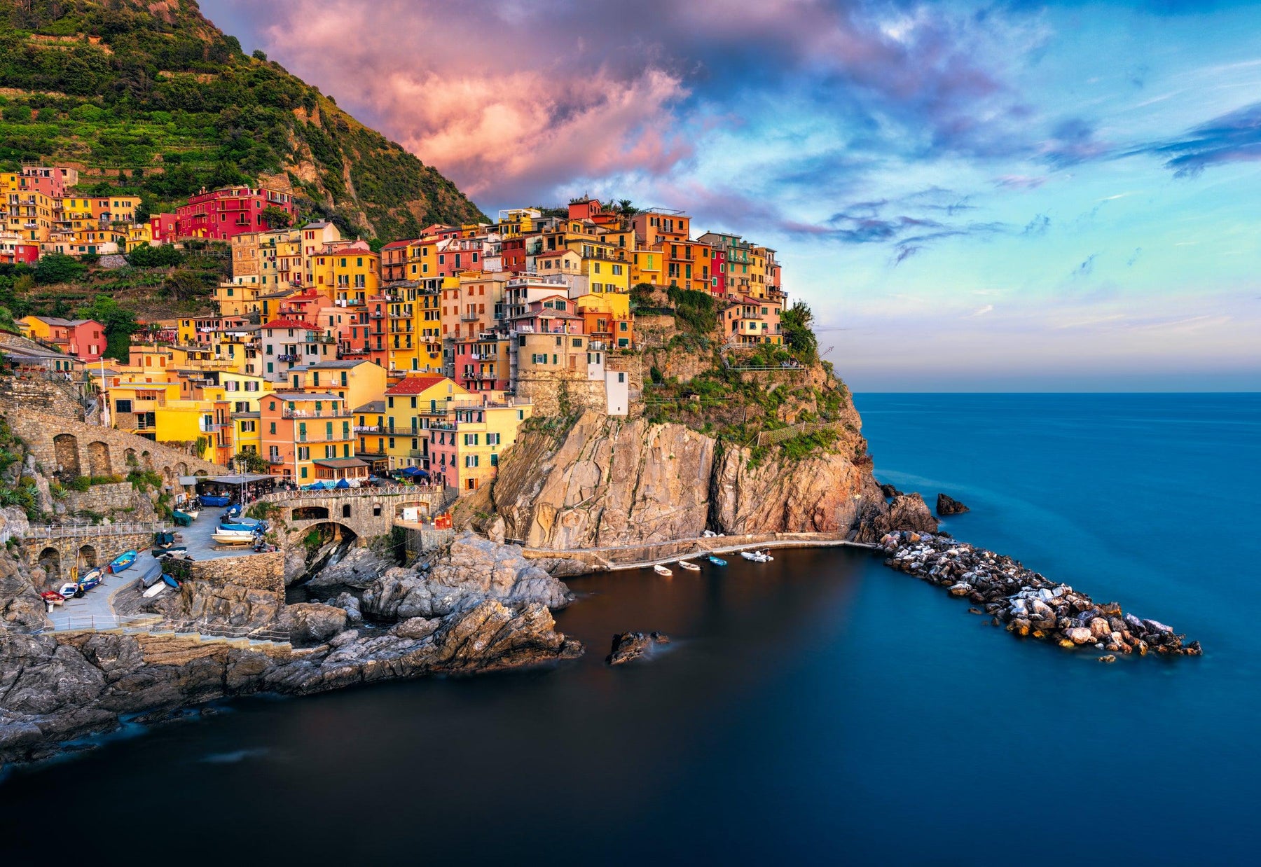 Colorful painted buildings of Manarola Italy built on a cliff overlooking the ocean at sunset