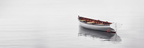 White wooden rowboat floating in the calm waters and misty cove in Martha's Vineyard Massachusetts
