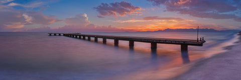 Old concrete jetty stretching out over the ocean and Cilento Coast Italy at sunset