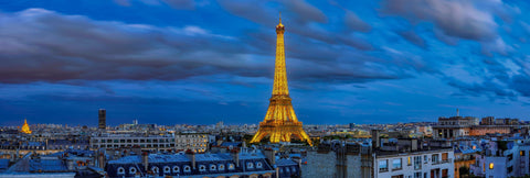 Paris France and the Eiffel Tower lit up at night under a cloudy sky