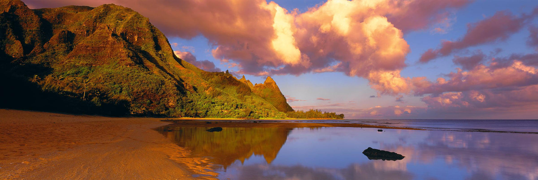Water filled tide pools reflecting the clouds and cliffs along the shoreline of the Na Pali Coast Hawaii