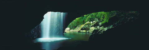 View from the inside of a cave looking out with water falling from a hole in the ceiling in Lamington national Park Australia