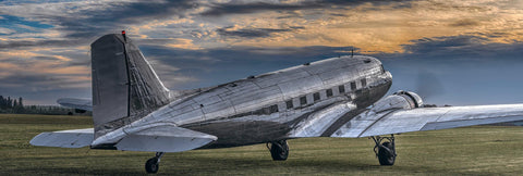 Side view of a DC-3 airplane taking off from a grass runway in Portland Oregon