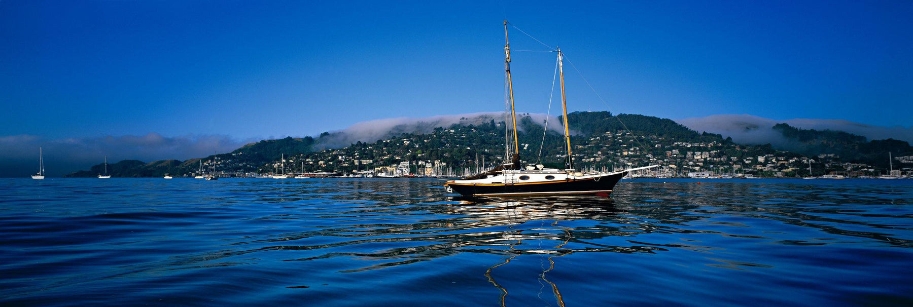 Sail boat reflecting in the middle of Richardson Bay with Sausalito Bay in the background