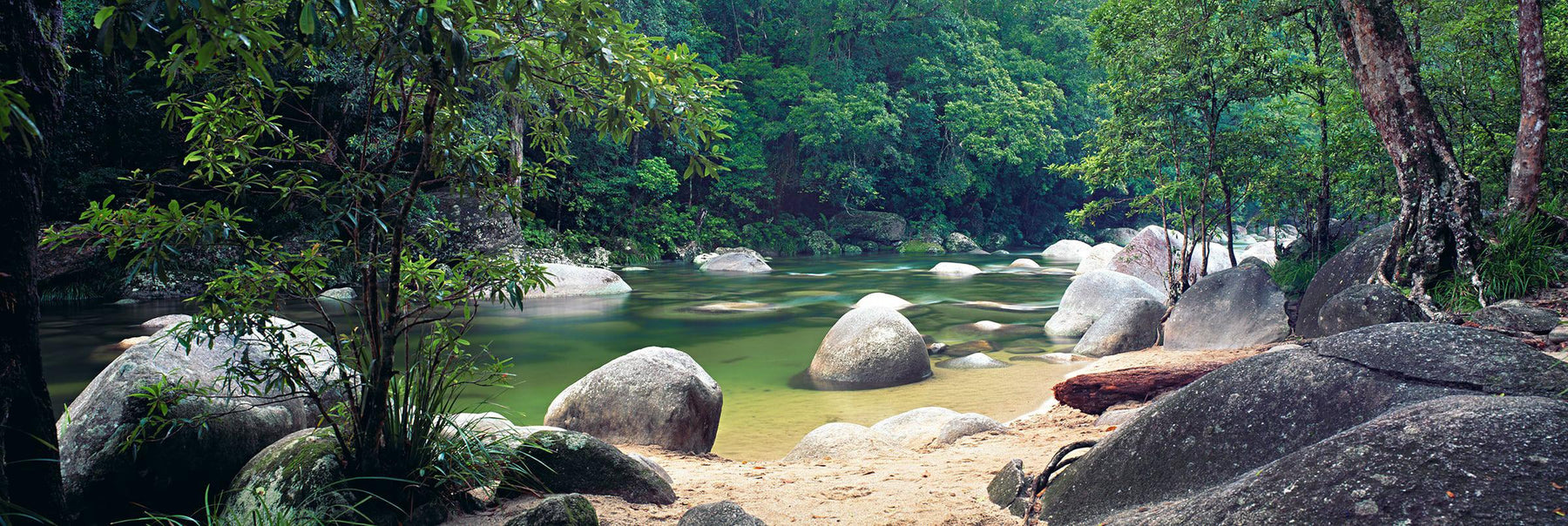 Rock and sand shore of the river running through the tropical rainforest of Mossman Gorge Australia