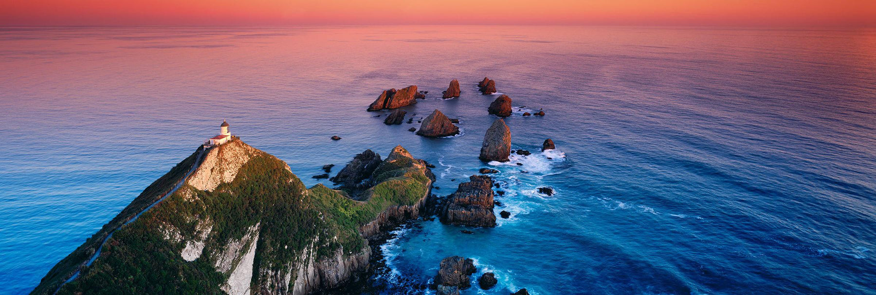View looking down on Nugget Point Lighthouse that sits on a cliff overlooking the Catlins coast in New Zealand