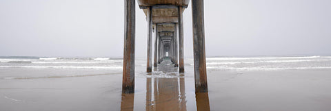 View from under Scripps Pier in California during a foggy morning with waves crashing in the background