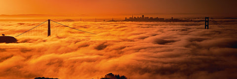 Thick clouds covering the Golden Gate Bridge with the city of San Francisco in the distance during sunrise