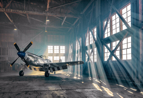 P51 Mustang airplane in a metal hanger and sun shining through the windows
