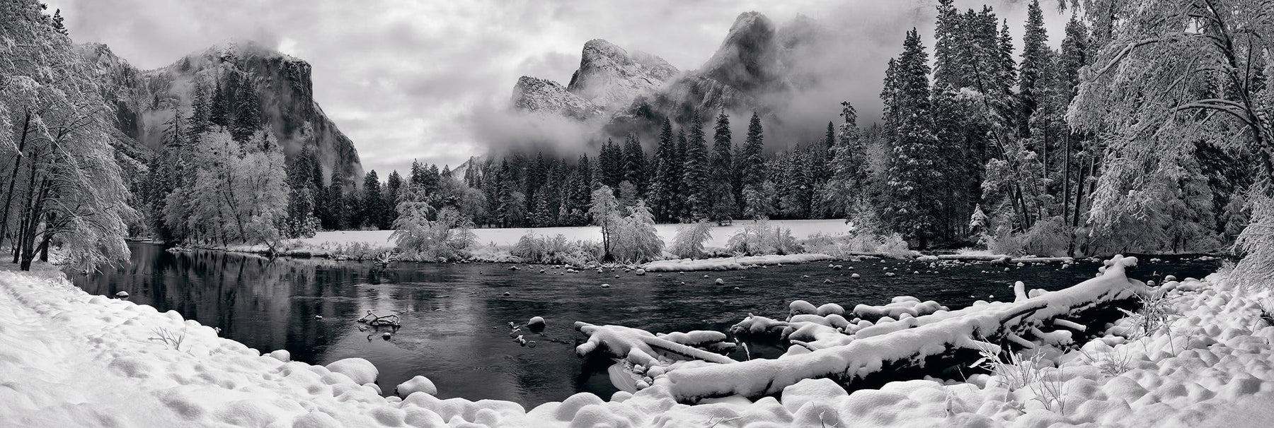 Black and white river running through the snow covered Yosemite Valley with El Capitan mountain in the background 