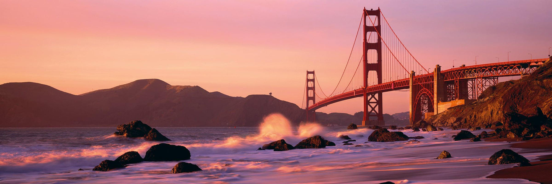 Waves crashing on the rocks of Baker Beach California with the Golden Gate Bridge in the background