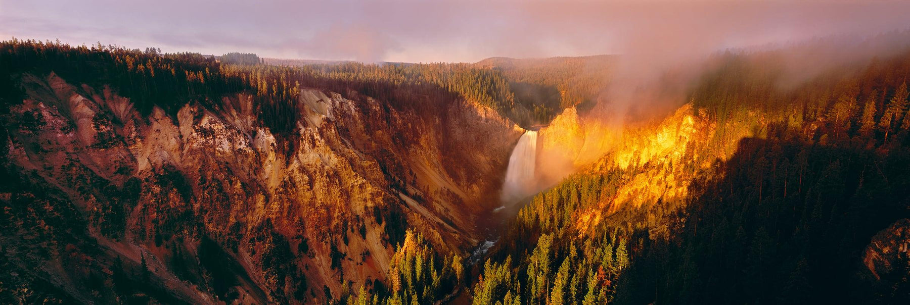 Sunlight hitting the mist covered waterfall and mountainside of Artist Point Yellowstone National Park Wyoming
