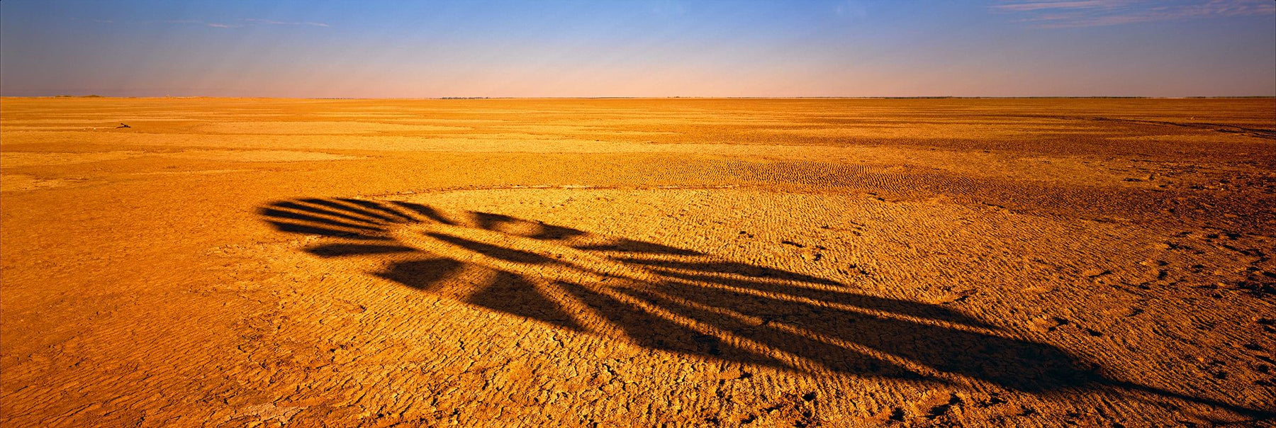 Shadow of a windmill blades being cast onto the dry desert floor in Normanton Australia